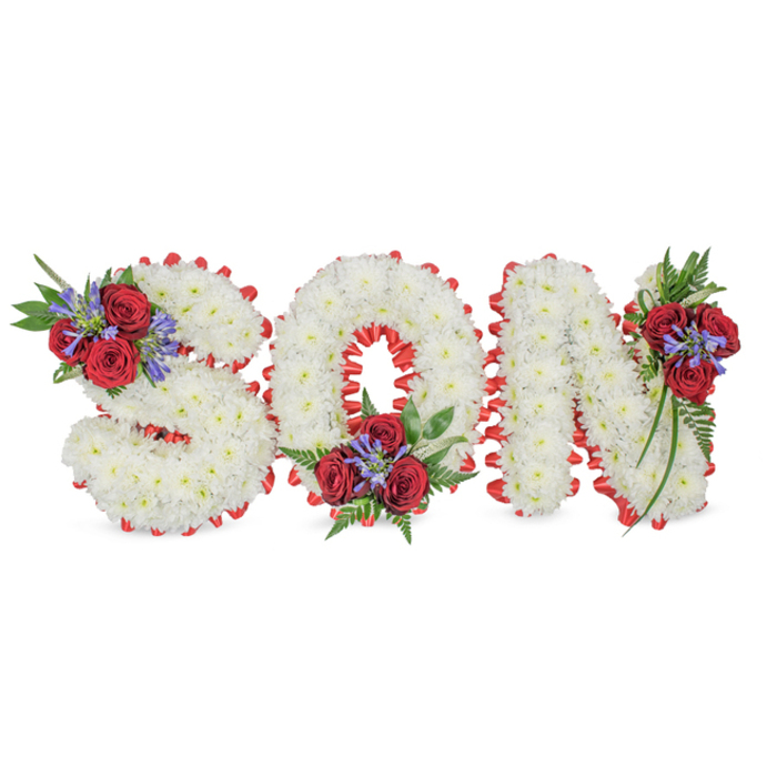 A poignant, handcrafted floral tribute set on a clean white backdrop spells out the word SON in bold, three-dimensional lettering formed entirely from small white chrysanthemums. The chrysanthemums are densely packed so each letter reads as a soft mound of petals-compact, tactile and visually serene-while the entire composition is rimmed with a striking red satin trim folded into a scalloped edge that crisply defines each character. Tasteful accent clusters provide deep colour and movement: the 'S' is highlighted at its top-left curve, the 'O' at its bottom centre, and the 'N' at its top-right, each cluster composed of rich, velvety red roses, upright blue-purple spikes (Liatris-style) and deep green foliage including delicate ferns and trailing leaves that spill slightly into the letter forms. The red trim and roses give warmth and solemnity against the pure white chrysanthemums, a traditional pairing that suggests love, remembrance and peace. Crafted with the sensibility of a local East London florist, the arrangement would be at home in memorial services across Stepney, Whitechapel and nearby Whitechapel Road chapels, where understated, dignified tributes are chosen to honour a son's memory. The composition balances visual clarity for viewing in a sanctuary with intimate detail appreciated up close-the satiny ribbon, the matte petal texture, the faint, fresh scent of chrysanthemums-offering a measured, compassionate farewell.