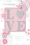 An anniversary card is displayed in gentle, even light, revealing a design that blends romantic softness with refined detail, much like a bespoke bouquet arranged for a Stepney couple. At the centre, the word LOVE stands proudly in raised, tactile letters. They are coated in soft glitter, predominantly blush pink with pearlescent white glints and slender outlines of silver, allowing the word to shimmer subtly as the card moves, like sunlight touching petals in a quiet Stepney courtyard. The letter O is transformed into a glimmering heart, textured with denser silver glitter that makes it the most eye-catching point of the composition, symbolising the emotional core of the anniversary. Surrounding this central motif, a halo of delicate, stylised blossoms and gentle vines in shades of blush, mauve, and pale grey extends across the card. Their appearance is slightly watercolor-soft at the edges, with fine pen-like details that recall a florist's sketchbook as they plan an anniversary arrangement for delivery near Whitechapel or along Commercial Road. Tiny flourishes-swirling lines, scattered dots, petite petals, and discreet butterflies-introduce a feeling of motion, as though a light spring breeze has just swept through an English garden. At the top or bottom of the design, the phrases On Our Anniversary and I love you today and always appear in an elegant, lightly looping script. The typography is clear yet romantic, reinforcing the message of ongoing devotion. The overall impression is of a cherished keepsake, soft and intimate, perfectly paired with fresh flowers sent across Stepney to mark another year of shared life and quiet, enduring romance.